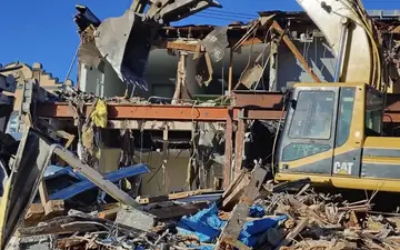 Excavator tearing out a damaged structure during an emergency demolition