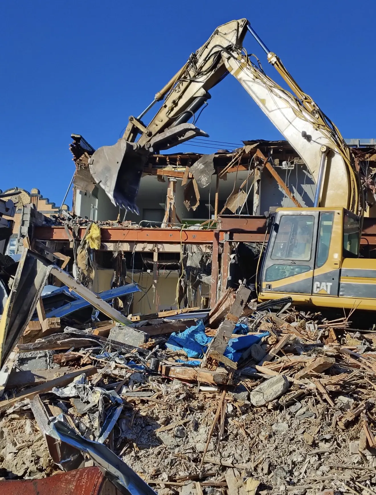 Excavator tearing out a damaged structure during an emergency demolition