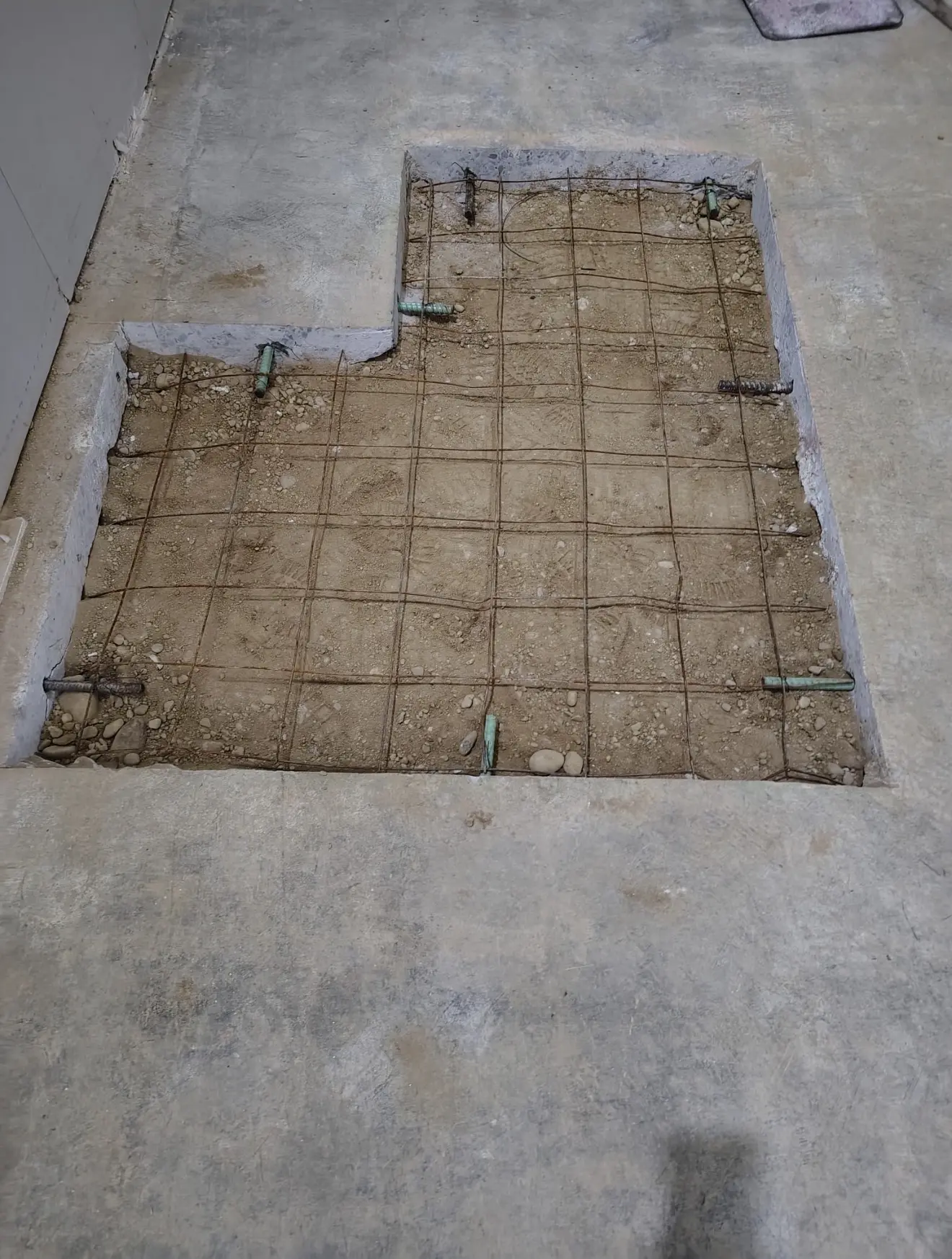 Selective demolition — a section of concrete slab cut out and removed, exposing rebar